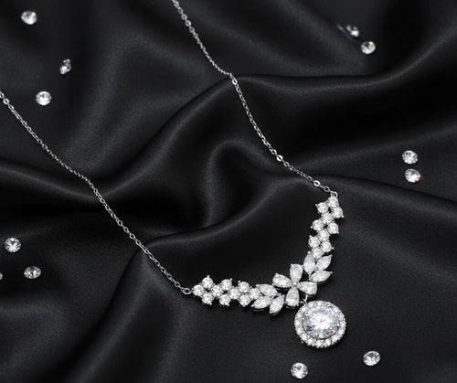 Elegant sterling silver necklace featuring intricate wing-like design with brilliant moissanite stones on neutral background.