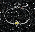 Sterling silver bracelet with yellow moissanite centerpiece in oval setting, crystal chain, and star charm on white background.