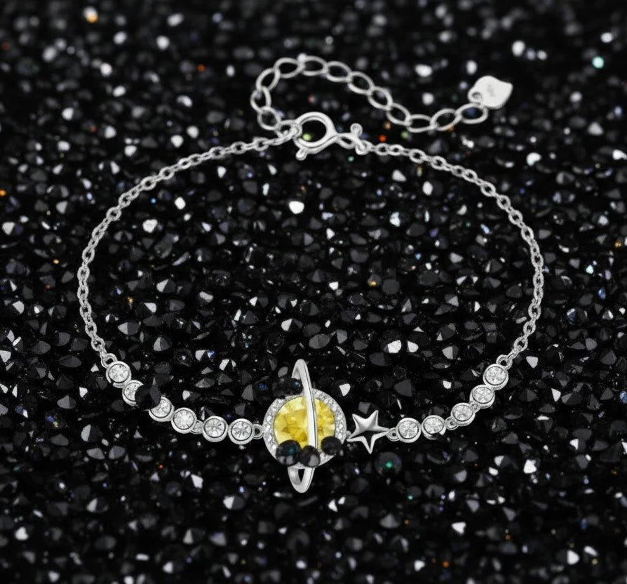 Sterling silver bracelet with yellow moissanite centerpiece in oval setting, crystal chain, and star charm on white background.